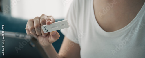 Asian young woman with hygiene protective face mask using SARS 2019-nCoV COVID-19 coronavirus antigen rapid test kit.