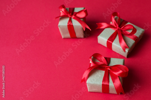 Festive concept - gifts with craft paper with a red bow on a red background. composition for christmas, new year and holidays. flat lay with place for text. 