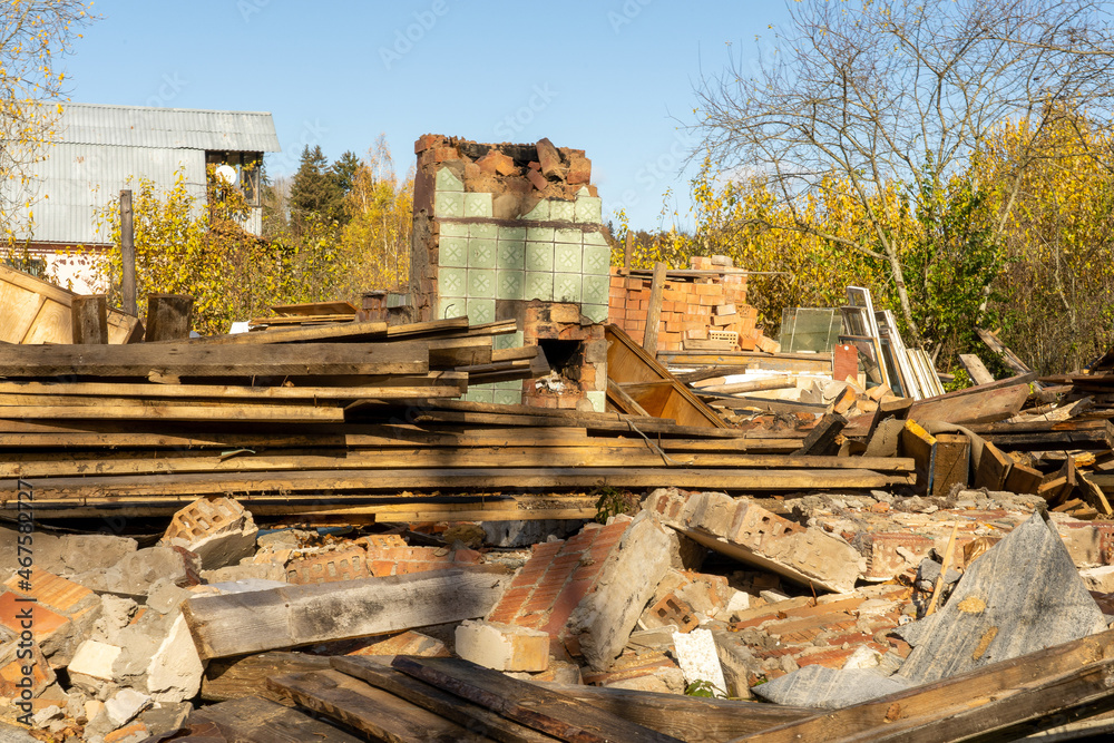Fototapeta premium Photo of ruin of an old red brick house against the background of garbage, rubbish and junk on the street