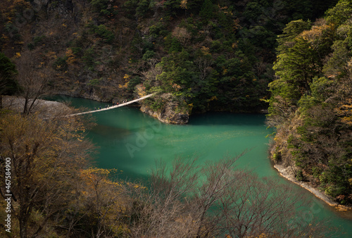 Landscape with suspension bridge over blue river in the middle of mountains with trees
