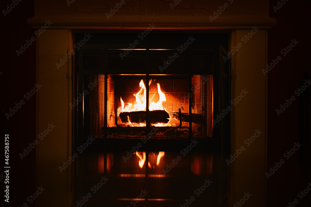 dark and warm picture of a wood-burning fire in a fireplace with a reflection at the bottom