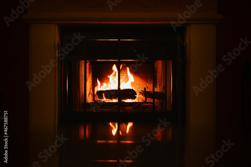 dark and warm picture of a wood-burning fire in a fireplace with a reflection at the bottom