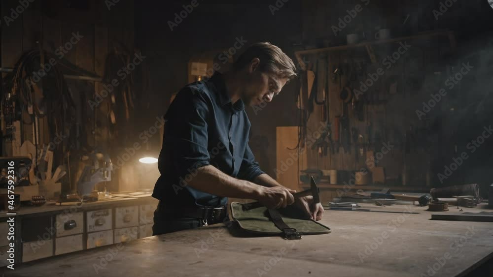 Professional man tailor beating off seams on handmade leather case, finishing original accessory Professional man tailor beating off seams on handmade leather case, finishing original accessory
