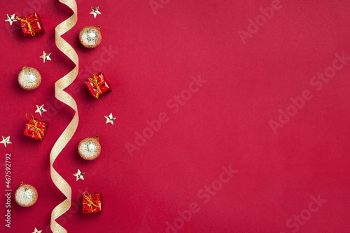 New Year or Christmas border or background with golden ribbon, golden balls, gifts and stars on red background, copy space. Mockup for postcards, business cards and other festive materials