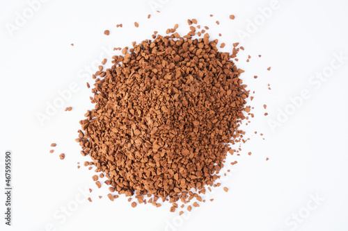 Freeze-dried instant coffee on white background close-up. Heap of powdered brown coffee product scattered on the table