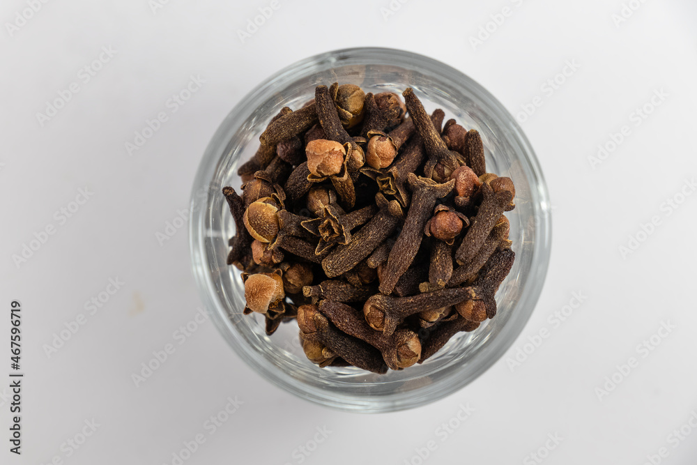Obraz premium Pile of organic fresh whole clove buds in glass bowl, scattered clove buds isolated on white background. close up.top view.