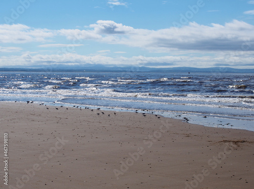 the beach at blundell flats in southport with waves braking on the beach and the wind turbines at burbo bank visible in the distance © Philip J Openshaw 
