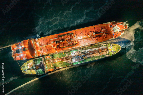 Two tankers at night, stand nearby in young ice. Shooting from air.