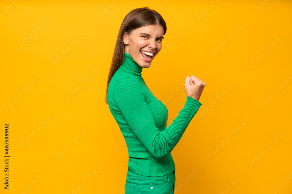 Young happy celebrating woman saying yes, she is a winner, isolated on yellow Young happy celebrating woman saying yes, she is a winner, isolated on yellow