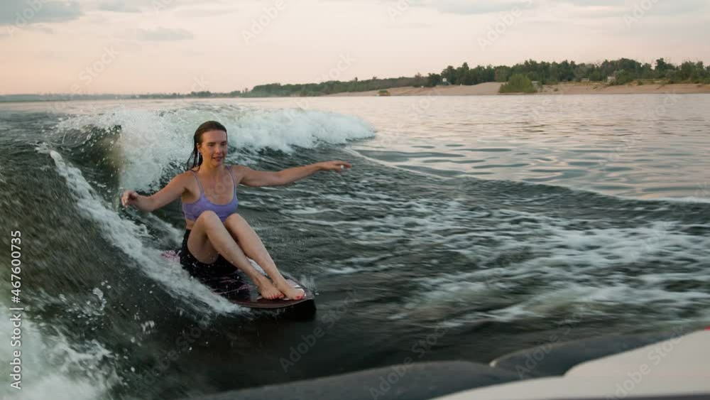 A female surfer jumping on a wakeboard. An experienced wakeboarder splashes water drops into the camera.