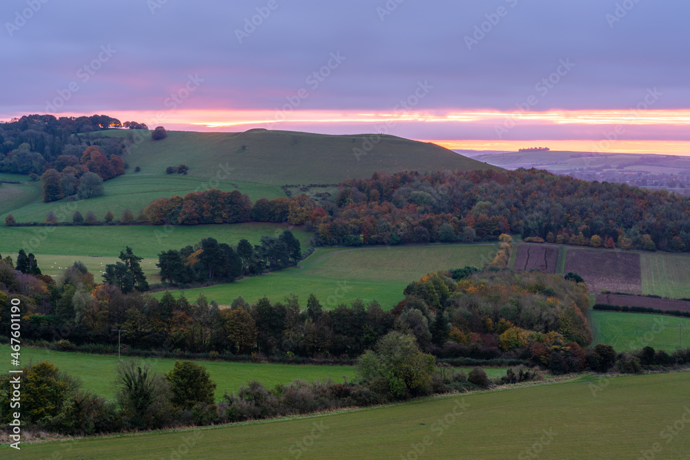 dramatic purple, red, pink and orange sky as the sun rises over Giant's Grave, Oare. View from South facing edge of the Marlborough Downs, Pewsey Vale, Wiltshire AONB 