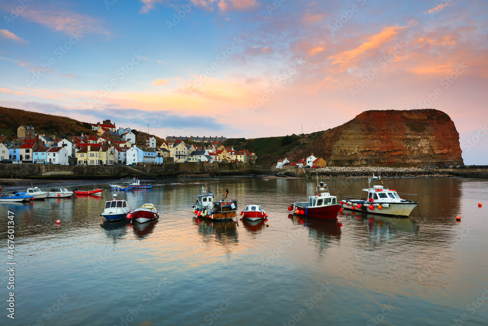 Naklejka premium Moored Boats in a Harbour at Sunrise, Staithes, North Yorkshire, England, UK.