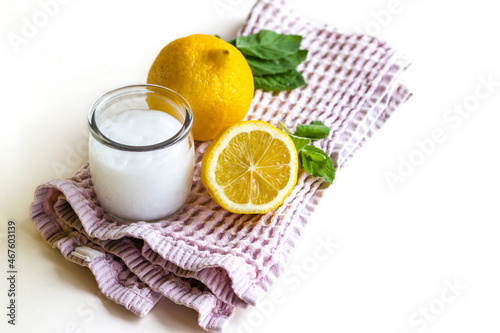 On the left side there is a cotton towel, there is a jar of cream on it, there are lemons and mint leaves. Concept: cosmetology, spa, healthy nutrition, medicine, vitamins.