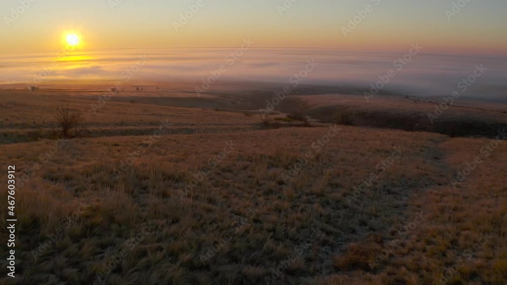 Aerial view of a sun upon a fog and hill. Slowly and smoothly going down to a valley at a dawn time. Sun at left upper third. Aerial view of a sun upon a fog and hill. Slowly and smoothly going down to a valley at a dawn time. Sun at left upper third.
