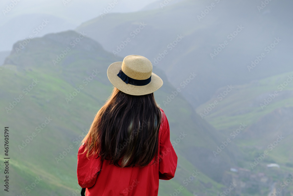 Girl with long hair and a hat enjoying a beautiful mountain landscape. Wanderlust and travel concept. Hiking journey on tourist trail