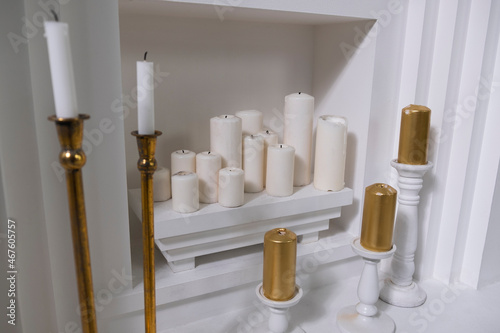 extinguished round wax white candles of different sizes on a white shelf in the wall