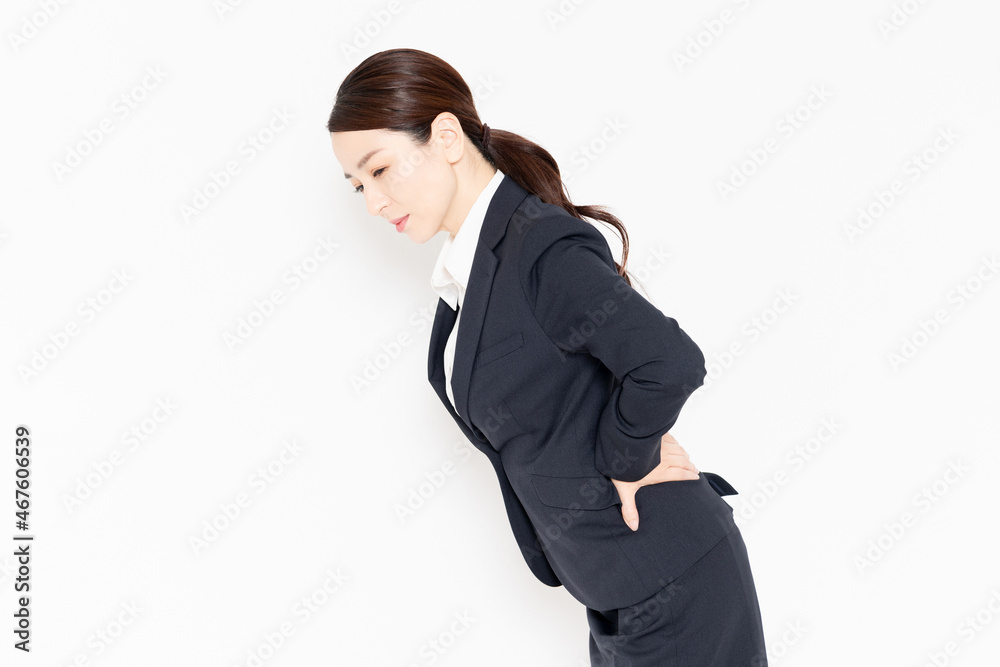 腰痛で腰に手を当てるビジネスウーマン