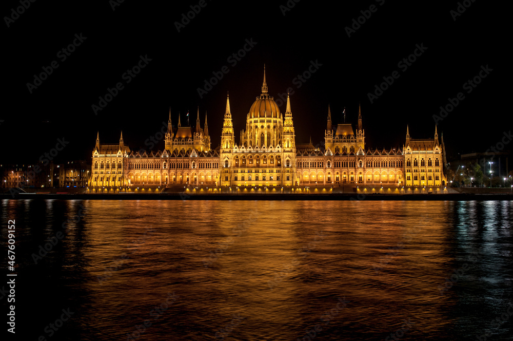 Night view from the waterfront on the Parliament of Budapest (Hungary), reflected in the river Danube.