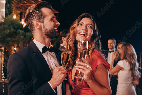 Beautiful young couple in formalwear toasting with champagne while spending time on luxury party photo