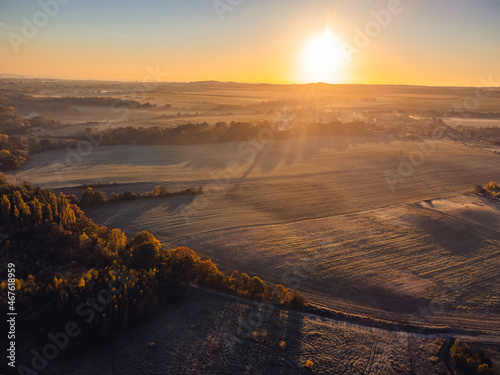 Aerial top-down view of autumn landscape at sunrise. There is a fine haze above the ground.