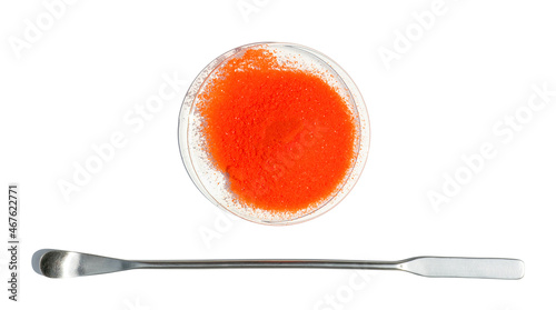 Potassium Dichromate in chemical watch glass placed next to the stainless spatula on laboratory table. photo