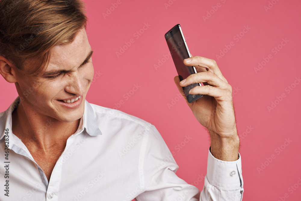 handsome man in a white shirt talking on the phone pink background handsome man in a white shirt talking on the phone pink background