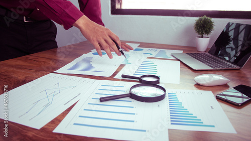 Business people use pen to point graphs to analyze company data and statistics from the chart.