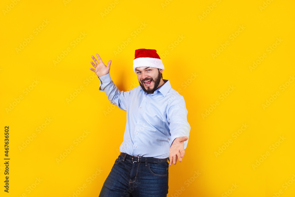 latin man in christmas concept pointing fingers right with santa hat, having fun, smiling amazed on a yellow background in Mexico Latin America