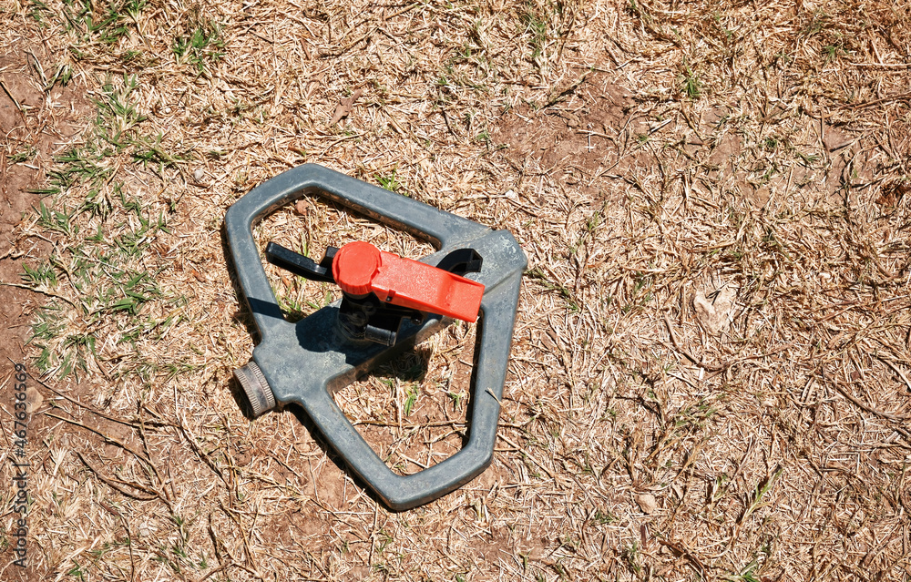 Detached plastic sprinkler on dry grasses of a garden. Global warming or climate change Detached plastic sprinkler on dry grasses of a garden. Global warming or climate change