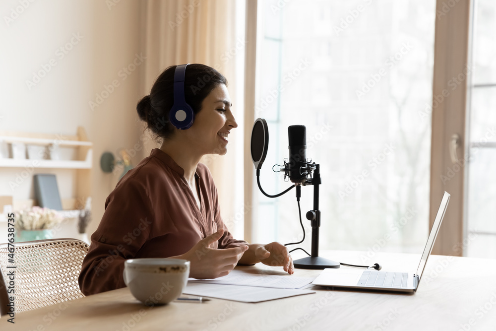 Young Indian ethnicity woman sit at table wear wireless headphones  recording podcast for internet audience on laptop makes speech using  microscope. Streaming services, on-line radio station concept Stock Photo |  Adobe Stock