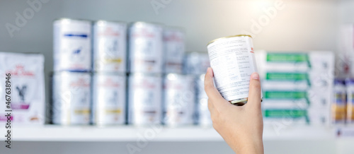 Fototapeta Naklejka Na Ścianę i Meble -  Women hand holding recovery canned food with defocus shelf background. Pet care concept