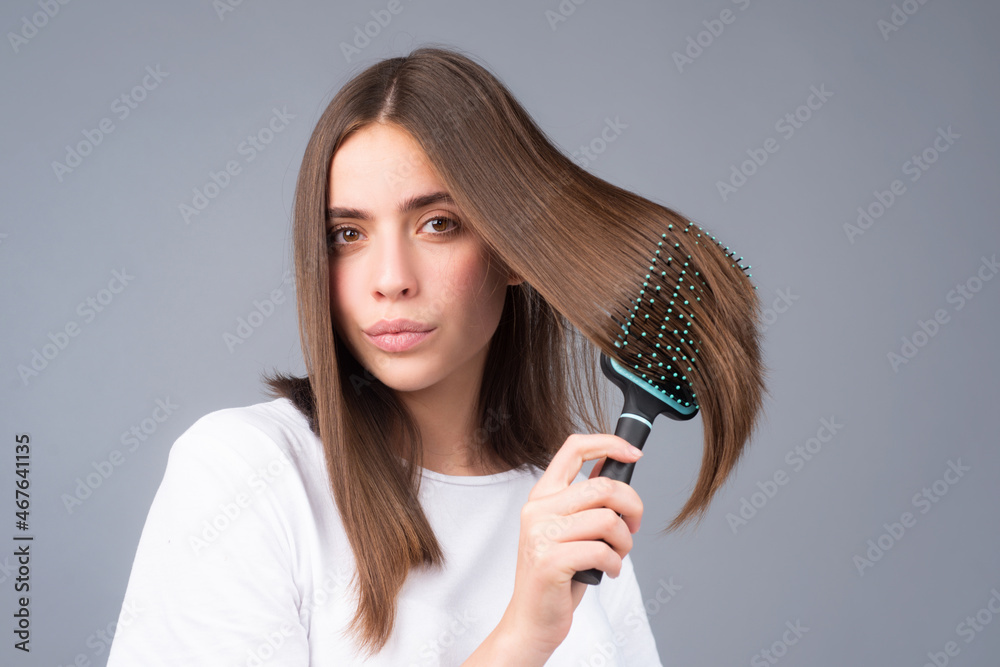 Portrait of beautiful young woman combing her hair, smiling. Female brushing healthy hair with comb. Portrait of beautiful young woman combing her hair, smiling. Female brushing healthy hair with comb.