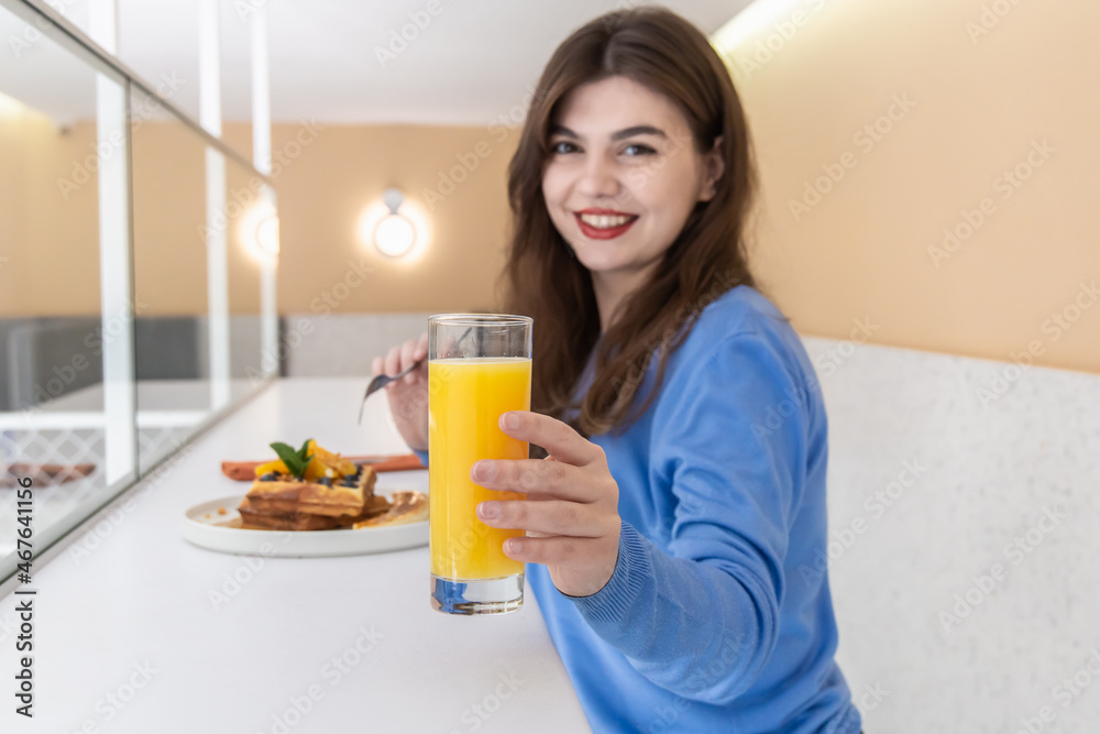 Attractive young woman eats Belgian waffles and juice for breakfast. Attractive young woman eats Belgian waffles and juice for breakfast.