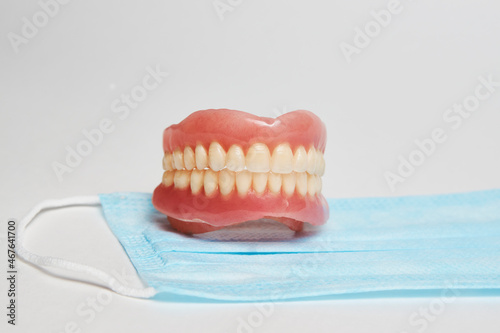 Dental dentures and medical mask on white background