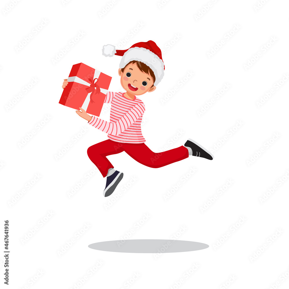 Happy little boy in Santa hat jumping while holding gift box feeling excited receiving Christmas present. Happy little boy in Santa hat jumping while holding gift box feeling excited receiving Christmas present.