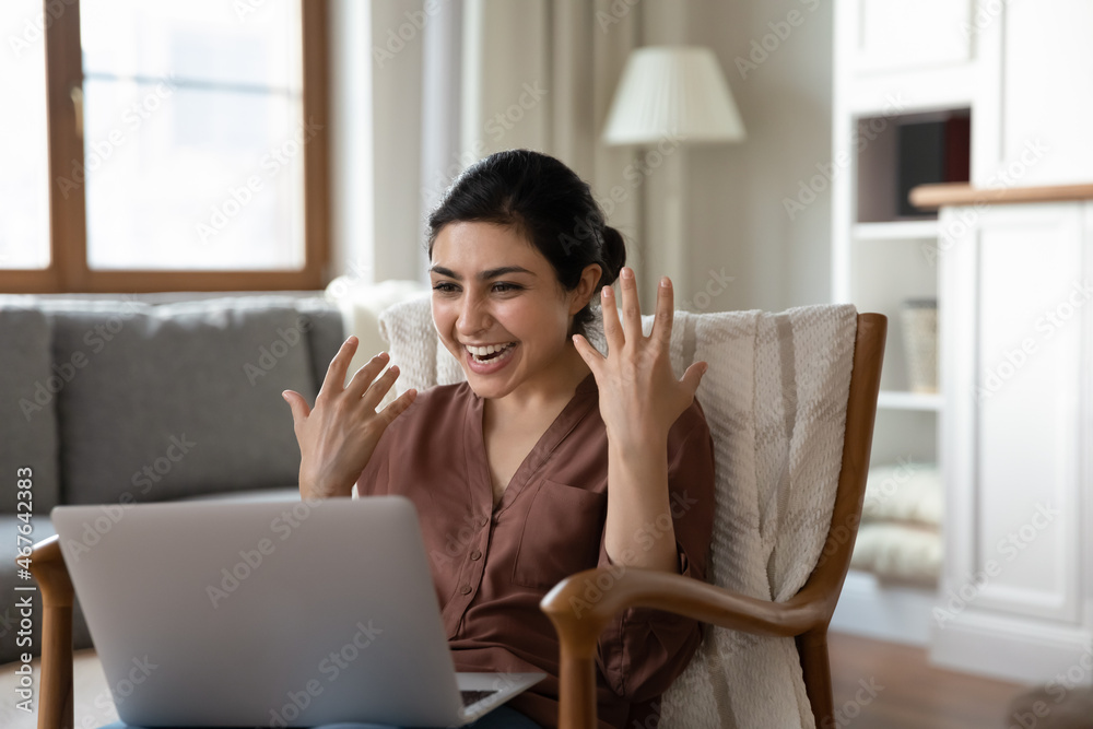 Overjoyed Indian woman sit in cozy armchair at home read great online news on laptop feels euphoric got pleasant message, celebrate success. Lottery victory, received money refund, sale, offer concept Overjoyed Indian woman sit in cozy armchair at home read great online news on laptop feels euphoric got pleasant message, celebrate success. Lottery victory, received money refund, sale, offer concept