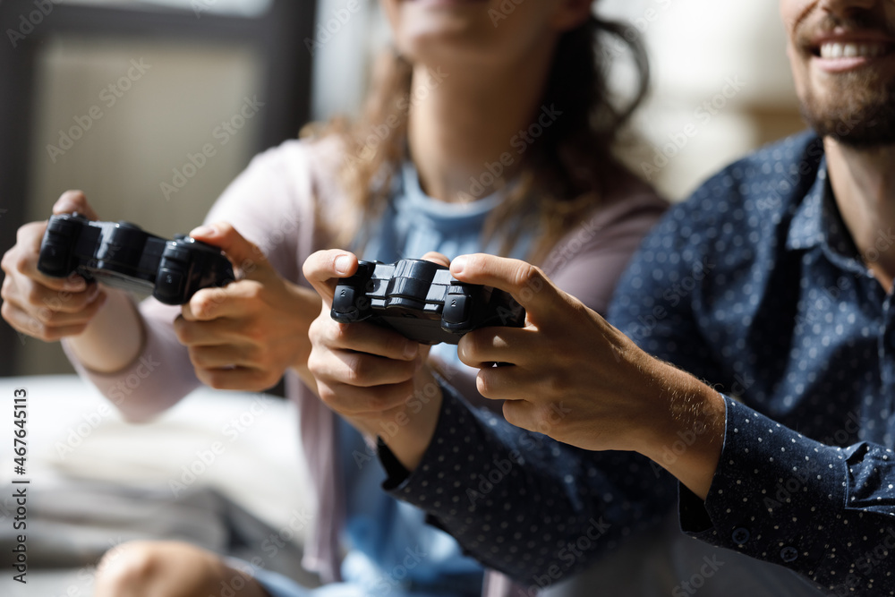 Close up joyful young woman man couple holding remote controllers in hands, spending time together playing online video game, enjoying virtual reality entertaining pastime, hobby activity concept. Close up joyful young woman man couple holding remote controllers in hands, spending time together playing online video game, enjoying virtual reality entertaining pastime, hobby activity concept.