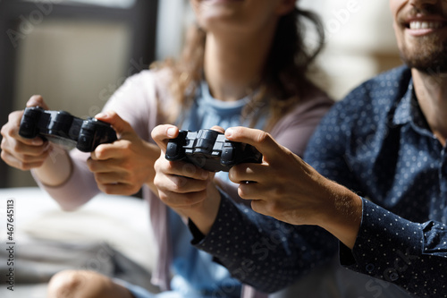 Close up joyful young woman man couple holding remote controllers in hands, spending time together playing online video game, enjoying virtual reality entertaining pastime, hobby activity concept.