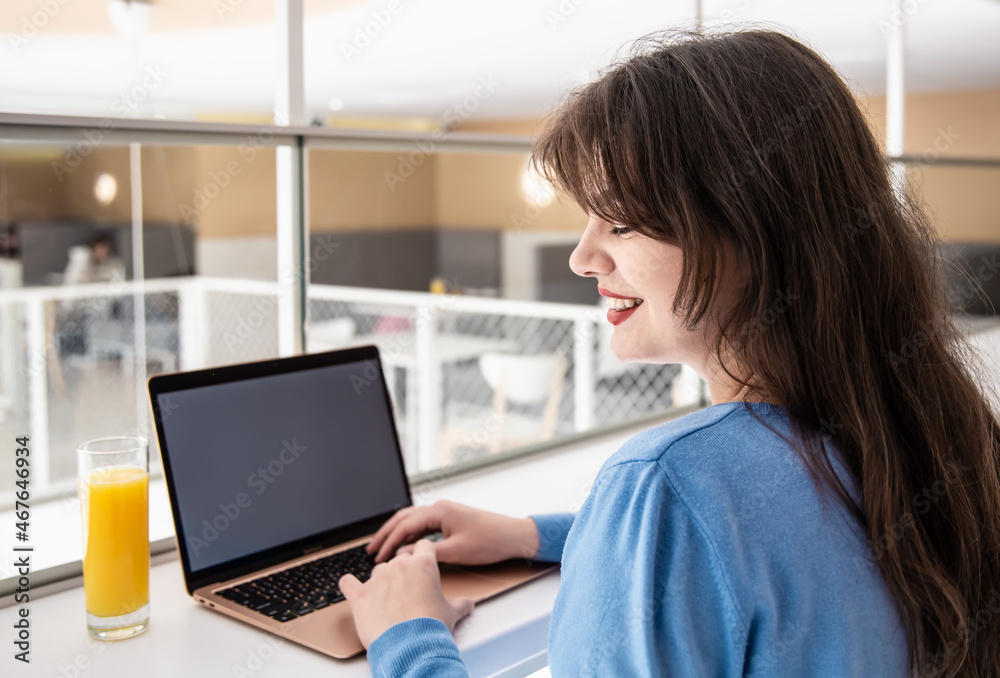 Attractive young woman with a glass of juice sits in front of a laptop. Attractive young woman with a glass of juice sits in front of a laptop.