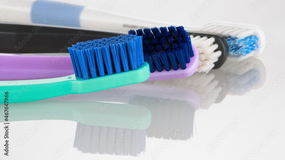 Bright tooth dental brushes of different colors on a white background with reflection