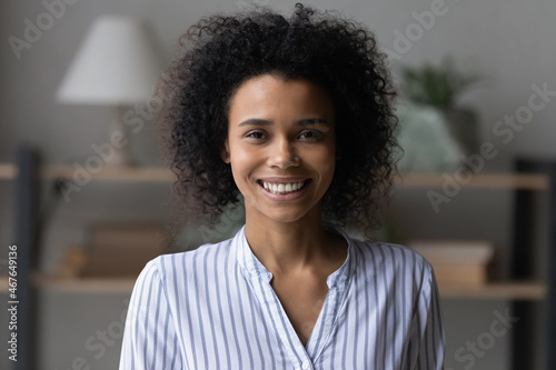 Head shot portrait of attractive African American woman, beautiful young female with healthy toothy smile and perfect skin looking at camera, happy homeowner tenant posing for profile picture at home