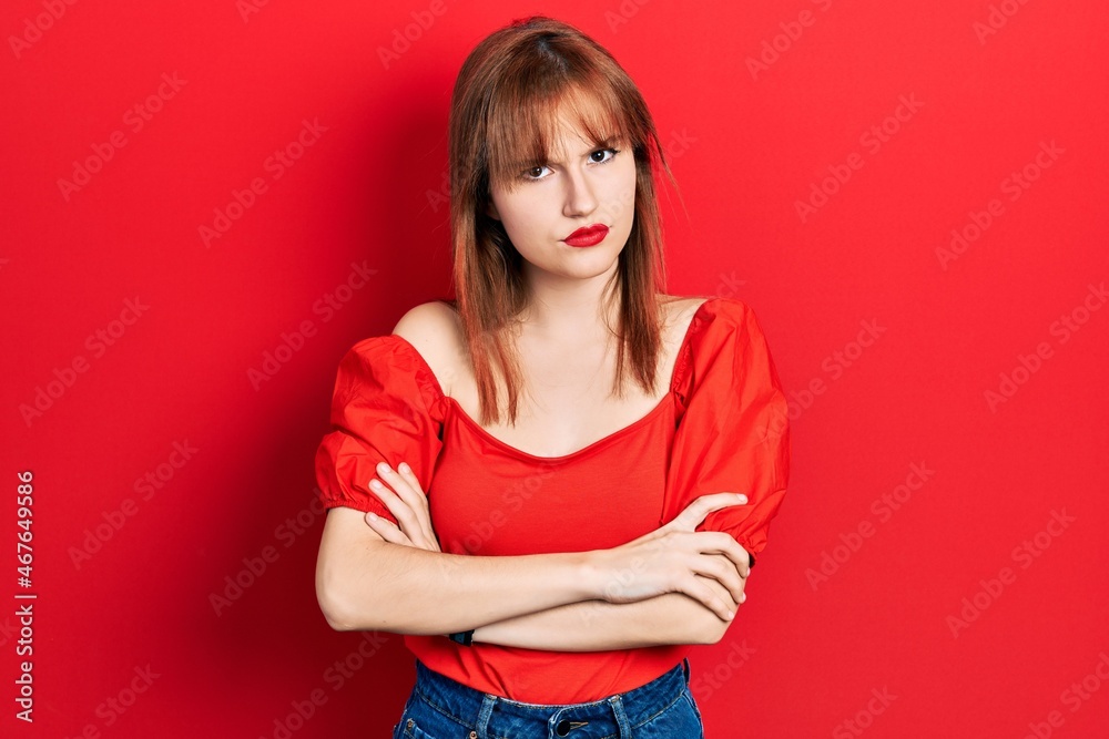 Fototapeta premium Redhead young woman wearing casual red t shirt skeptic and nervous, disapproving expression on face with crossed arms. negative person.