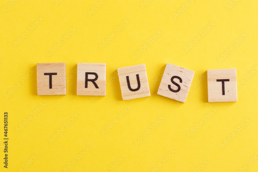Word TRUST made from wooden letters on yellow background Word TRUST made from wooden letters on yellow background