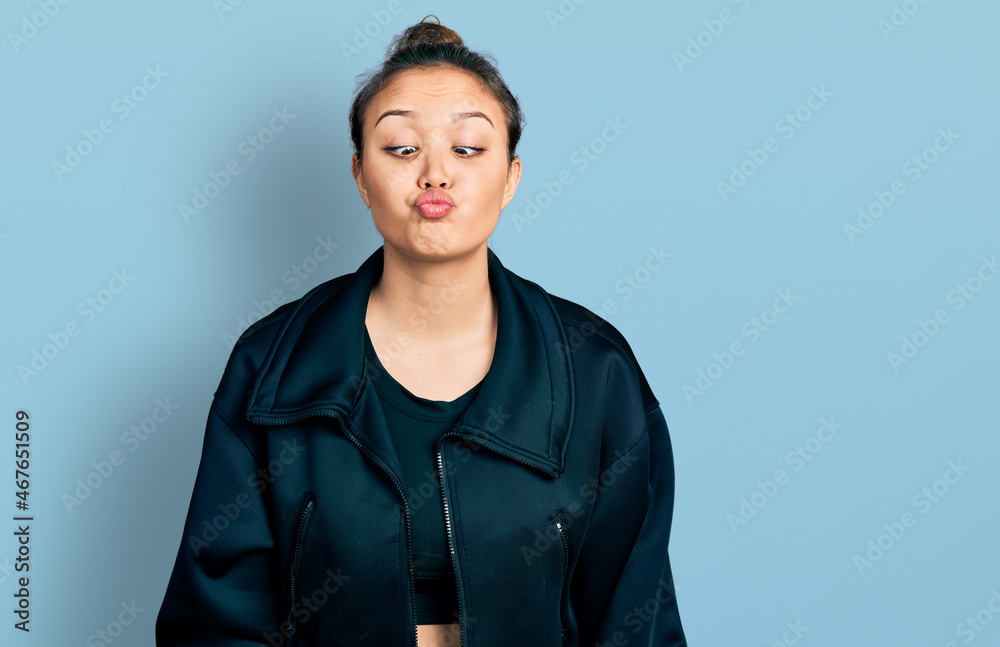 Young hispanic girl wearing sportswear making fish face with lips, crazy and comical gesture. funny expression. Young hispanic girl wearing sportswear making fish face with lips, crazy and comical gesture. funny expression.