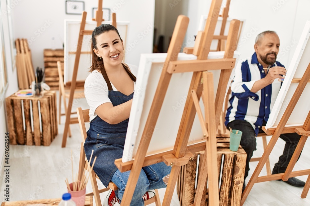 Young artist woman and senior painter man at art studio classroom painting on canvas with brush and oil painting Young artist woman and senior painter man at art studio classroom painting on canvas with brush and oil painting