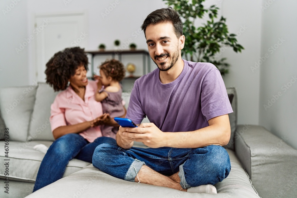 Couple and daughter using smartphone sitting on sofa at home Couple and daughter using smartphone sitting on sofa at home