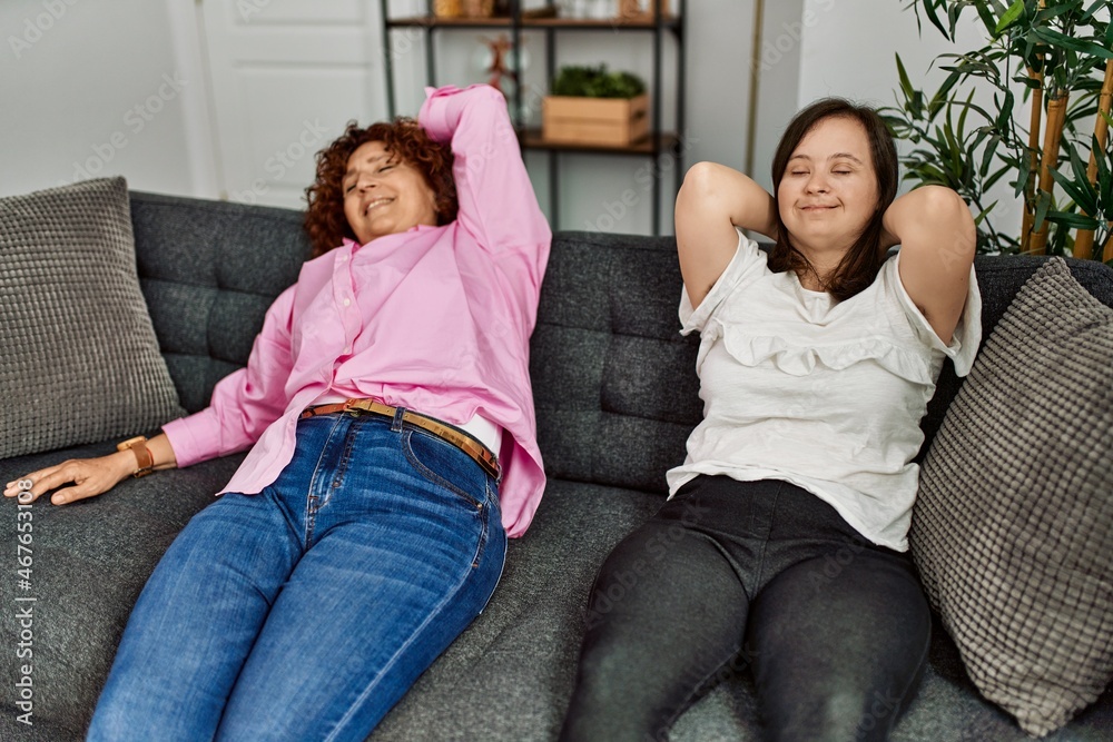 Mature mother and down syndrome daughter at home resting on the sofa Mature mother and down syndrome daughter at home resting on the sofa
