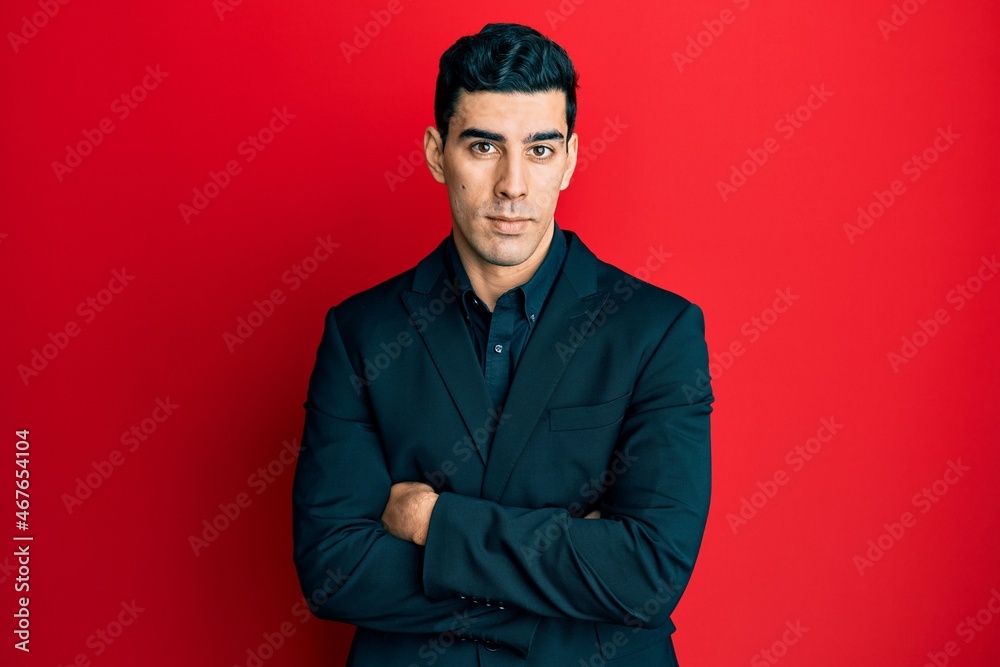 Handsome hispanic business man with arms crossed gesture relaxed with serious expression on face. simple and natural looking at the camera.