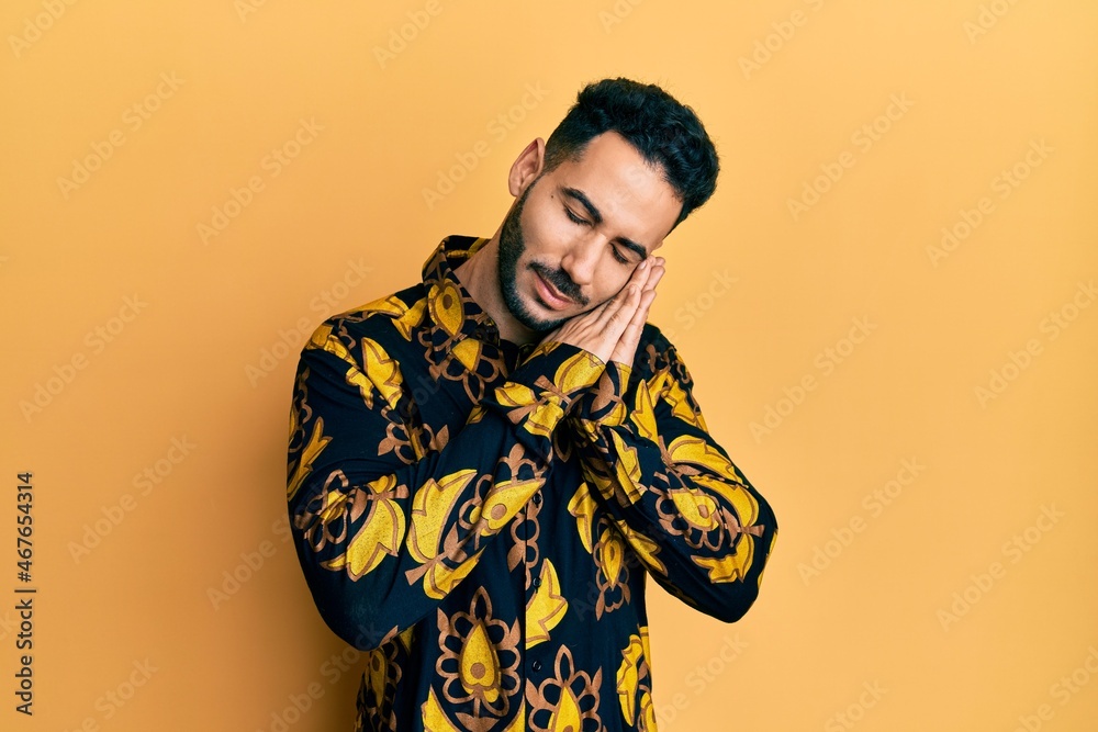 Young hispanic man wearing casual shirt sleeping tired dreaming and posing with hands together while smiling with closed eyes. Young hispanic man wearing casual shirt sleeping tired dreaming and posing with hands together while smiling with closed eyes.