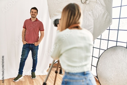 Handsome model posing for professional photographer woman at photography studio.